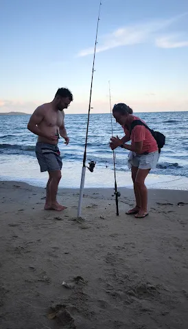 Two people beach fishing at the water's edge