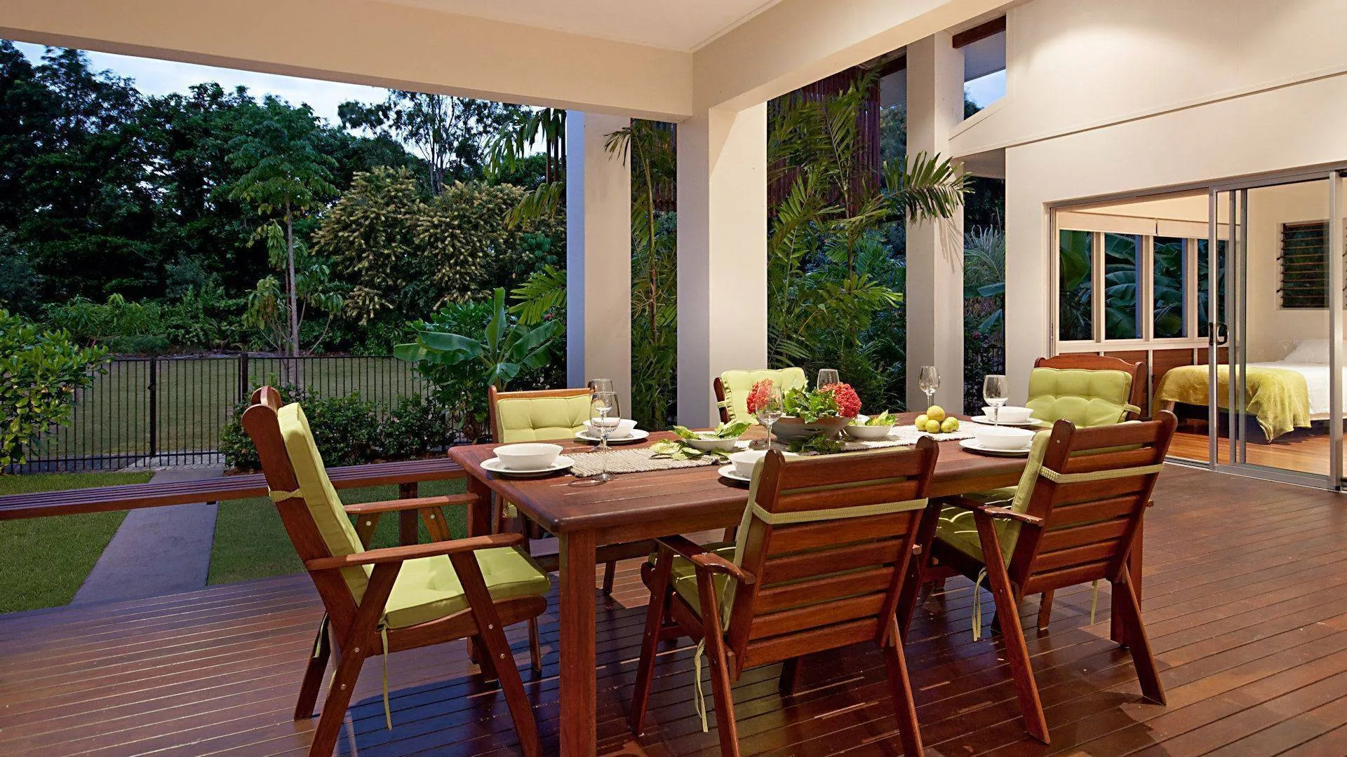Long timber dining table on the covered deck beside the garden