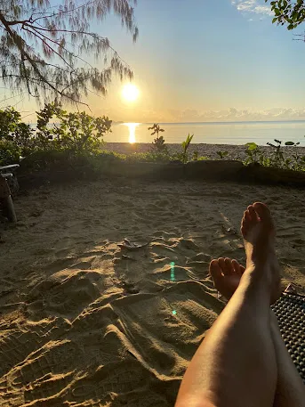 Bare feet in the sand under a shady tree