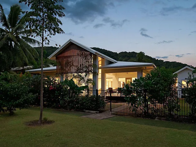 The house glowing among the palms at dusk