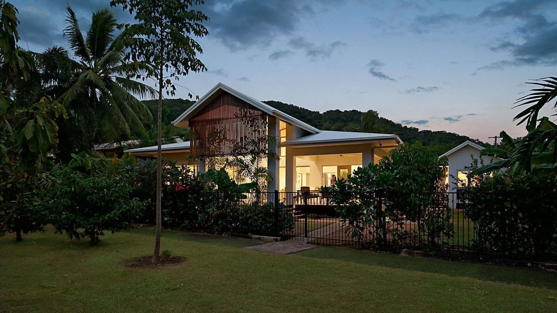The house glowing among the palms at dusk