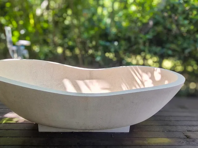 Stone outdoor bath on a timber deck under the palms