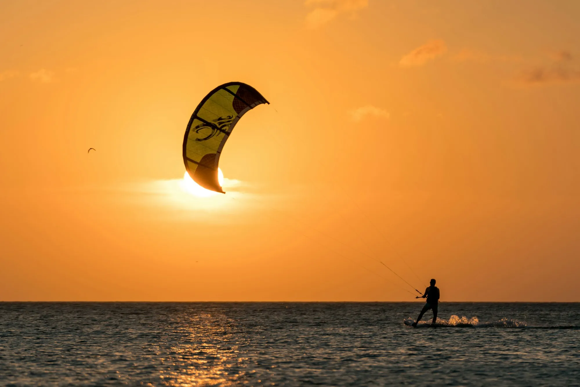 A kitesurfer silhouetted against a golden sunset